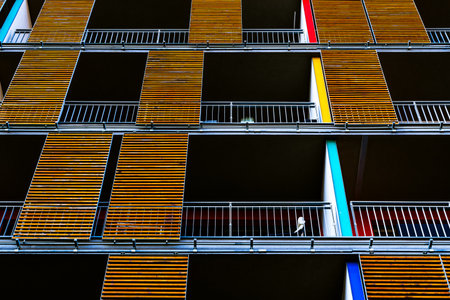 Modern Apartment Building Facade with Vibrant Yellow Wooden Panels and Spacious Balconiesの写真素材