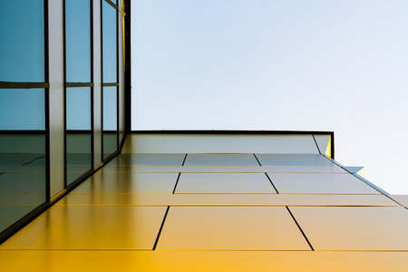 Minimalist Architecture with Golden Wall Panels and Reflective Glass Against a Clear Sky