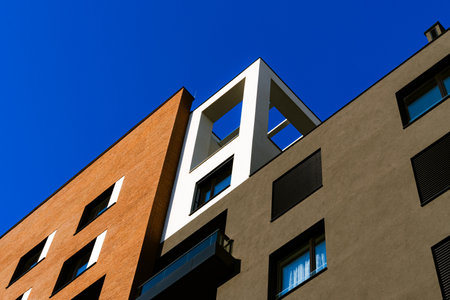 Modern Residential Complex with Contrasting Facades, Balconies, and Wooden Panels Under Clear Blue...