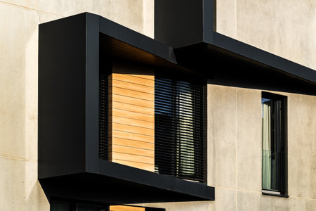 Modern Architectural Facade with Geometric Protrusions and Reflective Windows in Sunlightの写真素材