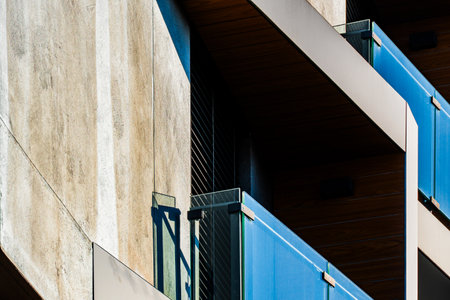 Modern Architectural Facade with Geometric Protrusions and Reflective Windows in Sunlightの写真素材