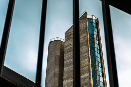 Brutalist Tower Viewed Through Metal Bars Against a Cloudy Sky, Strahov, Pragueの写真素材
