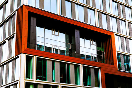 Modern Building Facade with Red and White Panels and Reflective Glass Windowsの写真素材