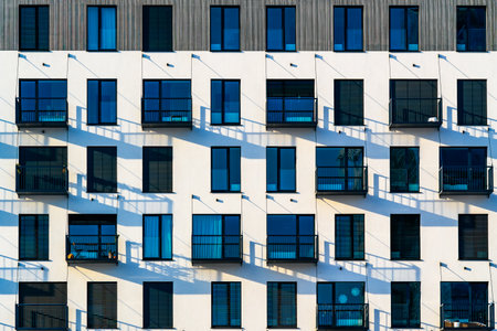 Modern Residential Building with White Facade, Large Windows, and Balconies Creating Unique Shadows