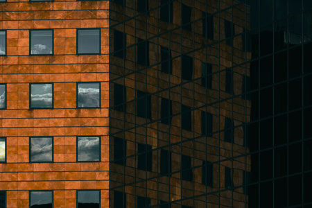 Modern office facade with orange cladding and dark blinds forming a repetitive geometric grid