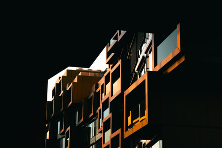 Modern residential facade with stacked orange balconies casting strong geometric shadows