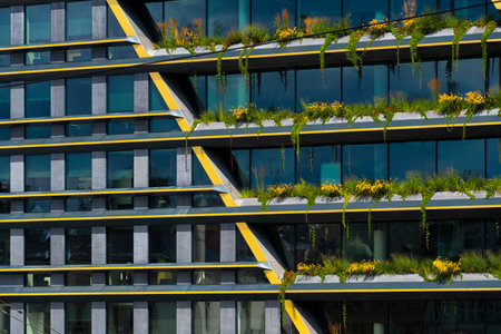 Office building with green terraces and bold yellow diagonal accents