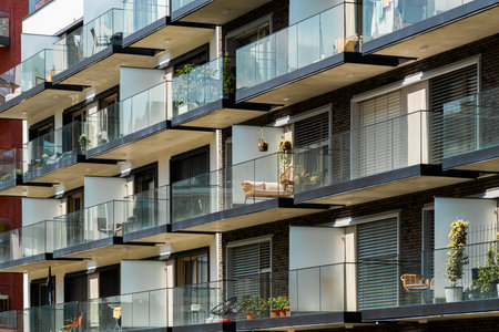 Contemporary glass-balcony apartment block with lush plants and outdoor furniture