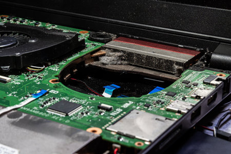 Close-Up of Dusty Laptop Cooling System with Heatsinks, Fan, and Circuit Board in Need of Cleaning