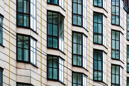 Repetitive bay windows on a contemporary facade with geometric rhythm and soft natural reflections