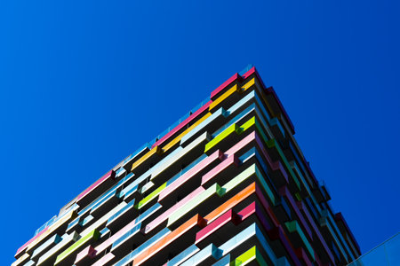 Colorful modern residential building with geometric balconies and vibrant facade pattern creating dynamic architectural rhythmの写真素材