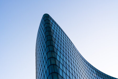 Contemporary office building with metallic facade and geometric glass design under clear deep blue...