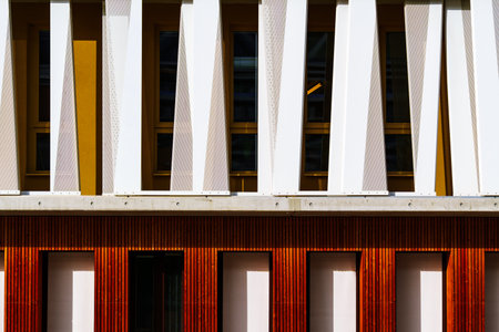 Modern office building facade with geometric white vertical panels and color tones in rhythmic...