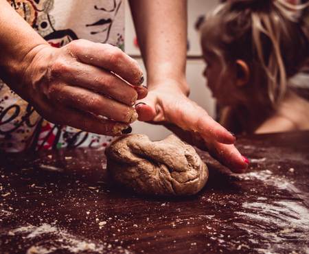 Skilful hands make dough on a wooden tableの写真素材