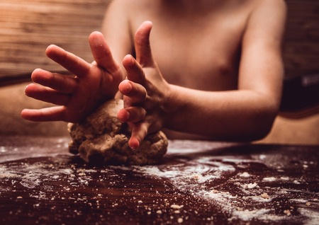 Skilful hands make dough on a wooden tableの写真素材