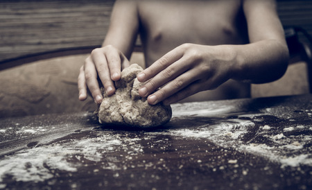 Skilful hands make dough on a wooden tableの写真素材