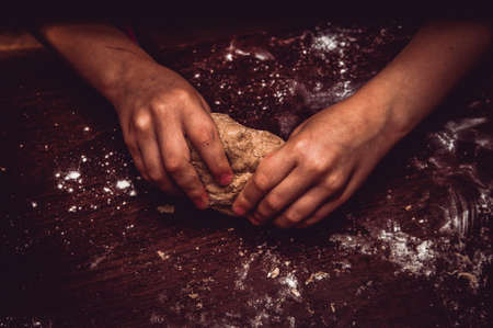 Skilful hands make dough on a wooden tableの写真素材