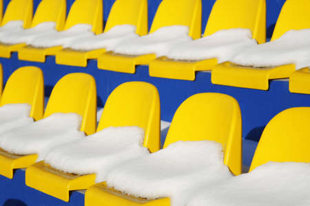 Yellow seats on tribunes of stadium under a snowの写真素材