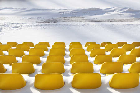 Yellow seats on tribunes of stadium under a snowの写真素材