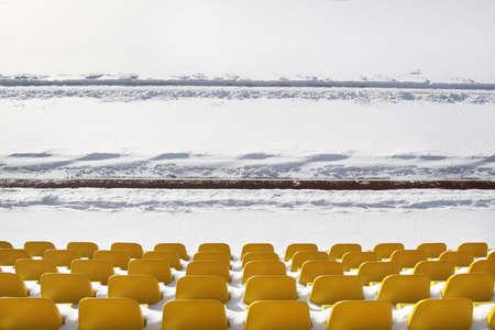 Yellow seats on tribunes of stadium under a snowの写真素材