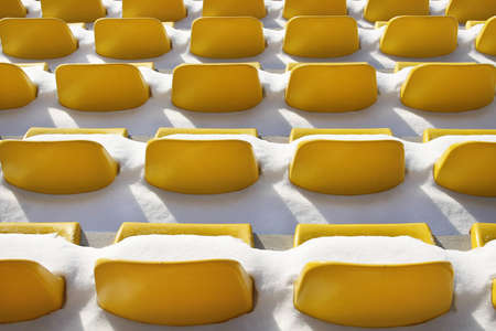 Yellow seats on tribunes of stadium under a snowの写真素材