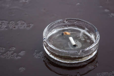 Ash-tray on black wet tableの写真素材