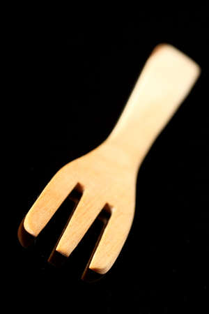 Closeup of a wooden kitchen fork over black backgroundの写真素材
