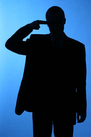 elegant man, businesman in  a suit pointing to his temple-sillhuetteの写真素材
