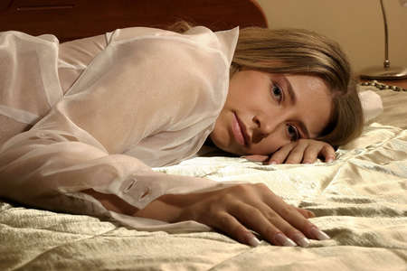 blond girl, young woman lying on a bedの写真素材
