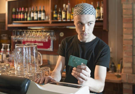 young  barman verifying credit card or cheatingの写真素材