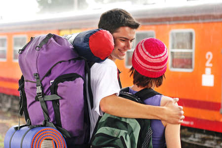 girl and a boy travelling with  backpacks-at a train stationの写真素材