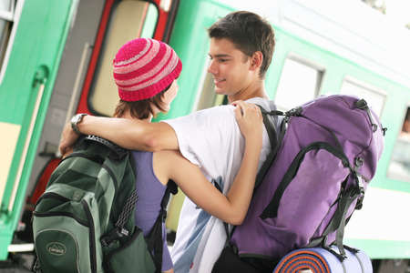 girl and a boy travelling with  backpacks-at a train stationの写真素材