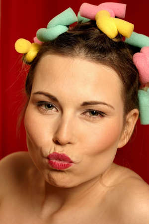close up of young woman with colourful curlers in her hair and red lipsの写真素材