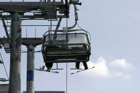 skiers on a chair-lift with a blue sky in backgroundの写真素材