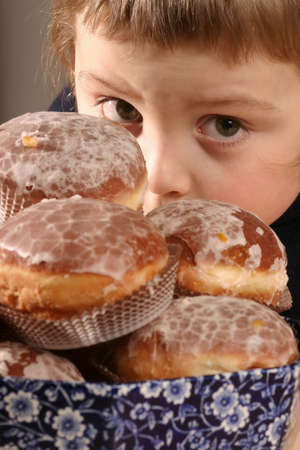 boy with fresh, iced donuts in a bowl-close upの写真素材