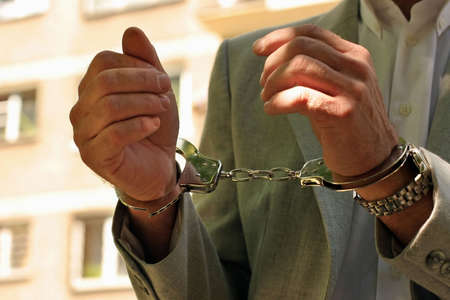 Arrested man in a business suit - hands in cuffs - close up 
