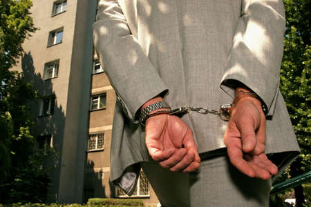 Arrested man in a business suit - hands in cuffs - close up 