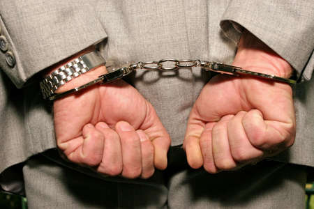 Arrested man in a business suit - hands in cuffs - close up 