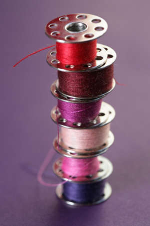 a view of colourful thread spools on a violet backgroundの写真素材