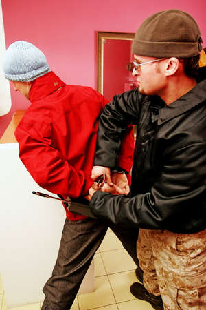 Bodyguard in a black jacket arresting and handcuffing an offender.の写真素材