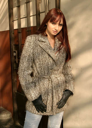 Young beautiful  girl with brown hair standing at a wall, with romantic look.の写真素材