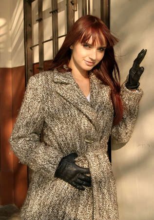 Young beautiful  girl with brown hair standing at a wall, with romantic look.の写真素材