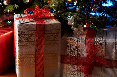 Two christmas gifts under the christmas tree with a red ribbon.の写真素材