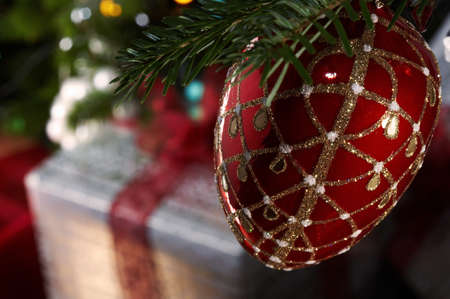 Christmas gifts under the christmas tree with a red bauble in a foregroundの写真素材