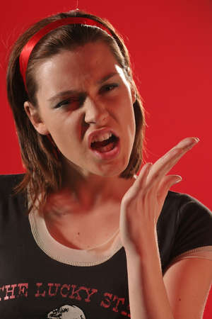 Young angry woman in a brown Tshirt on a red background making gesture.の写真素材