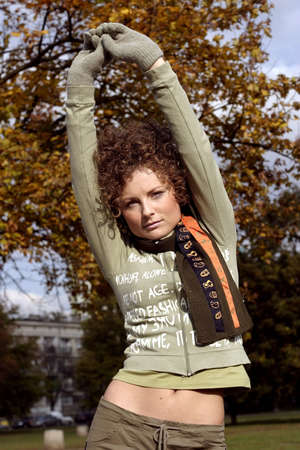 A young woman in a scarf stretching in a  park after long run.の写真素材