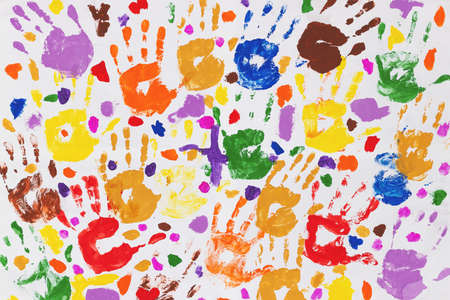 Colored prints of childrens hands on a white canvas. A childs handprint on paper. Colored handprints. Many childrens multi-colored handprintsの写真素材