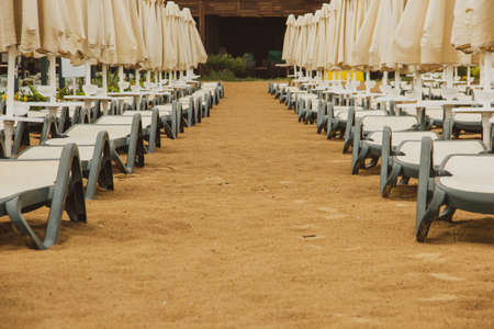 Empty plastic sun loungers by the seaside after the rain.