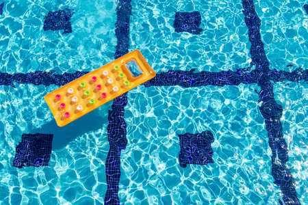 Orange air mattress floats in the pool. View from above.