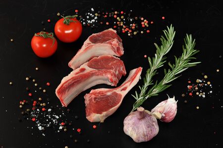 Raw lamb chops. Rack of Lamb with rosemary,  young garlic and spices on black background, top viewの写真素材